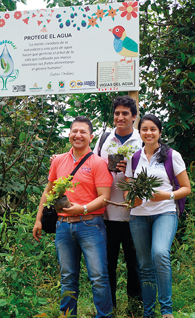 Imagen de la Universidad de Ibagué de tres estudiantes cada uno carga en sus manos una planta